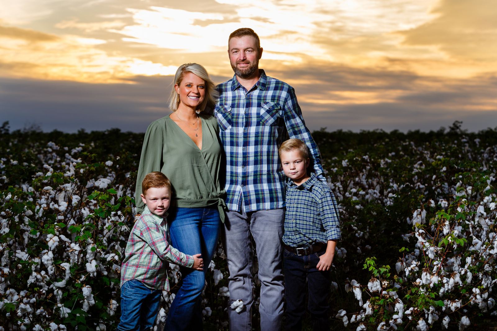 Jared Lott with his wife Ashlee and their sons Bryson and Brantley in a cotton field at sunset