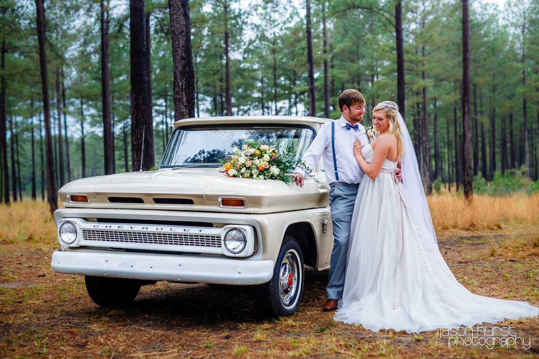 Bride and groom beside a vintage white Chevrolet truck in a pine forest